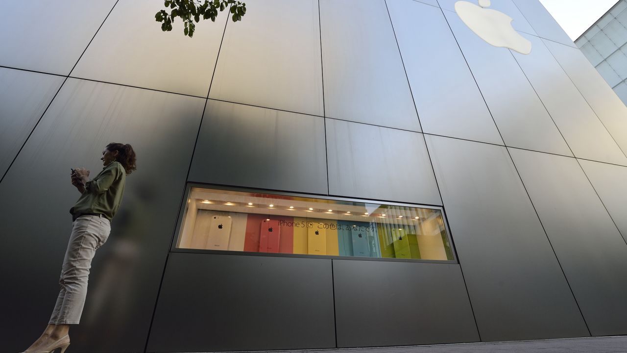 A woman uses her smartphone in front of a display for the Apple iPhone 5C outside the company's store in the Ginza district of Tokyo, Japan, on September 20, 2013.