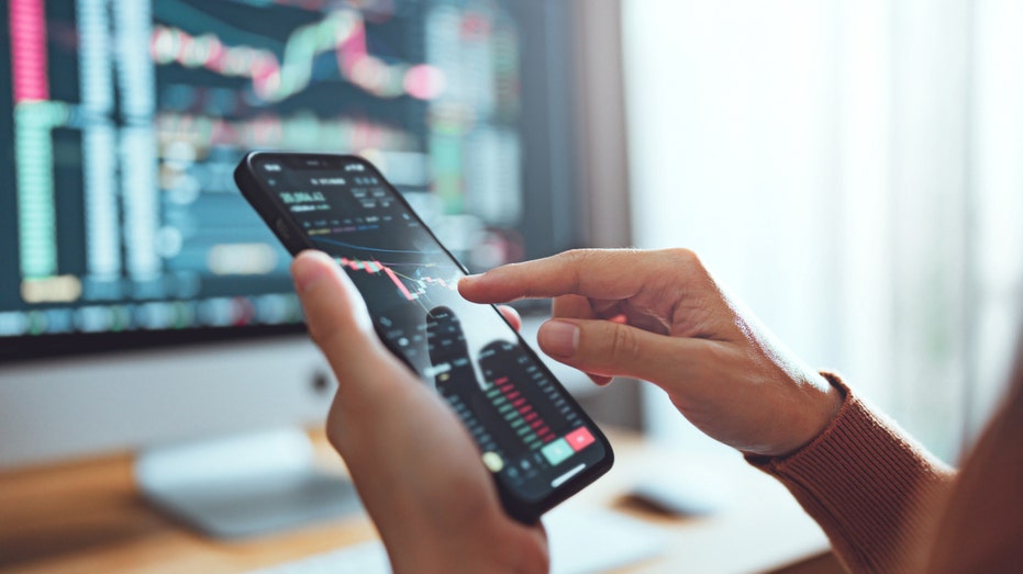 Close-up view a person's hands going over stocks on a smartphone.